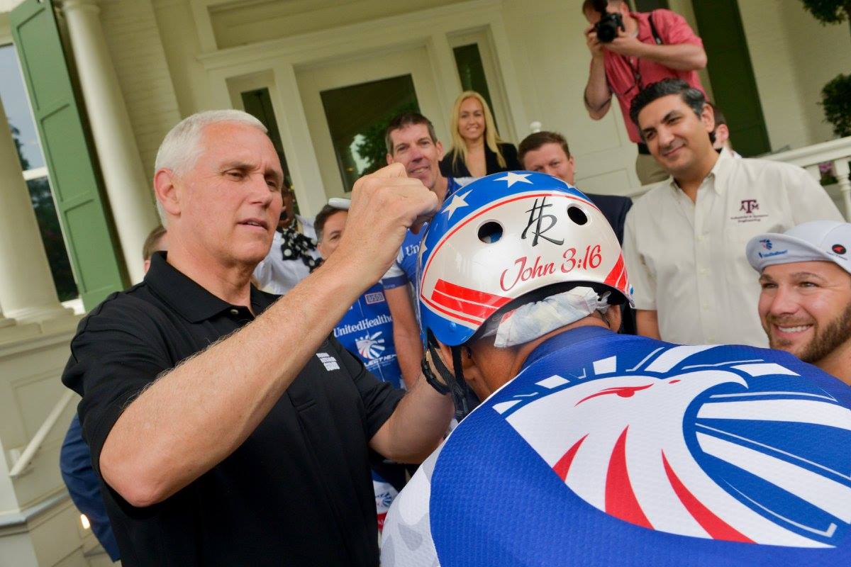 Vice President of the United States, Mike Pence signing an autograph on a bicyclist's helmet.