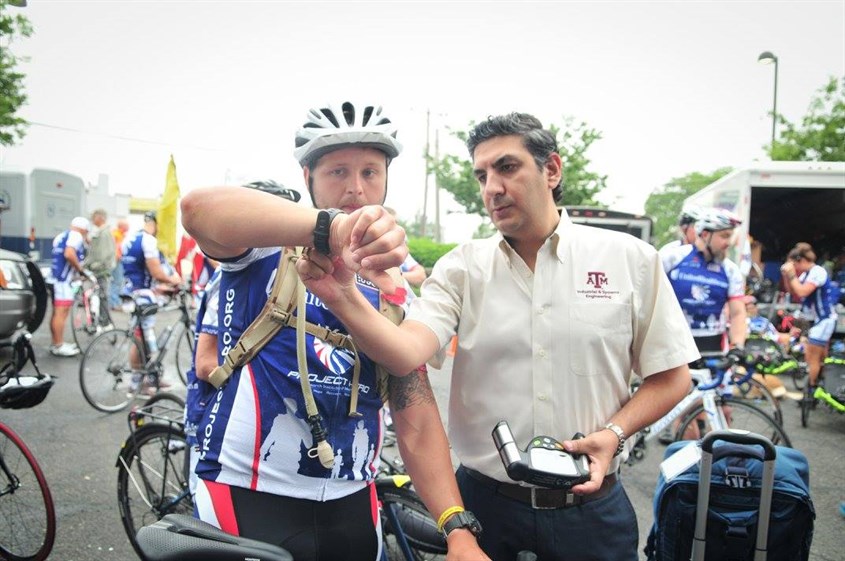 Dr. Farzan Sasangohar checking a wearable watch of a bicyclist.