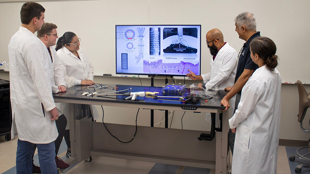 Lab personnel looking at information about a device for the trachea with other pediatric devices on the table