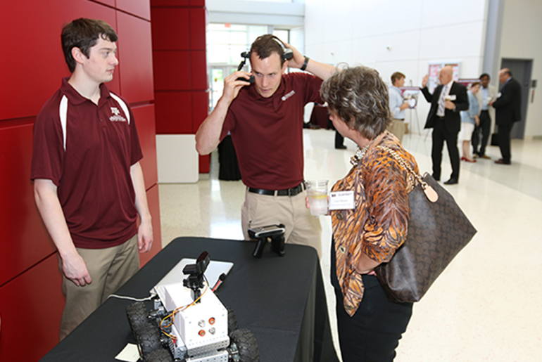 Two Researchers Demoing Their Robot To A Guest