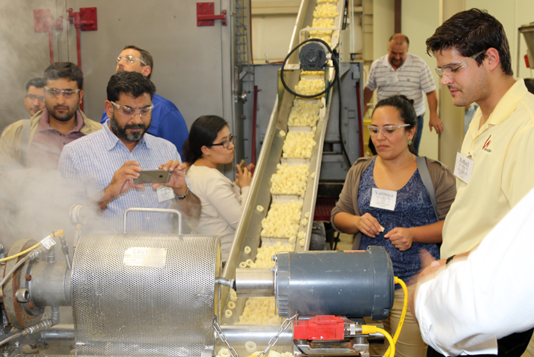 Short course attendees watch a demonstration of snack food production using a single screw extruder. 