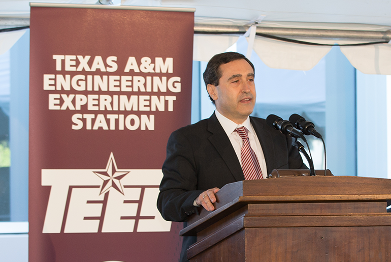 Dr. Christodoulos A. “Chris” Floudas Giving A Presentation With A Banner Of Words Texas A&amp;M Engineering Experiment Station TEES Behind Him