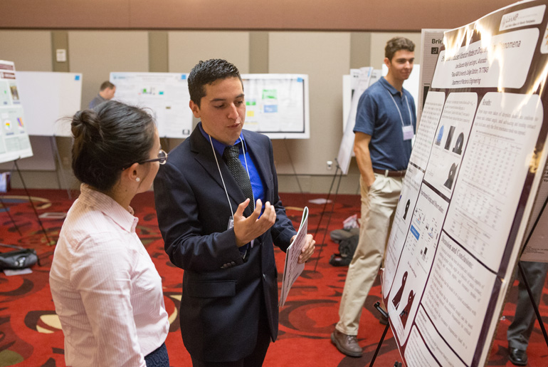 Jose Eduardo explaining his research to a woman at Conference on Energy.