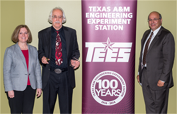 Photo of three individuals in front of banner with words of Texas A&amp;M Engineering Experiment Station TEES 100 Years