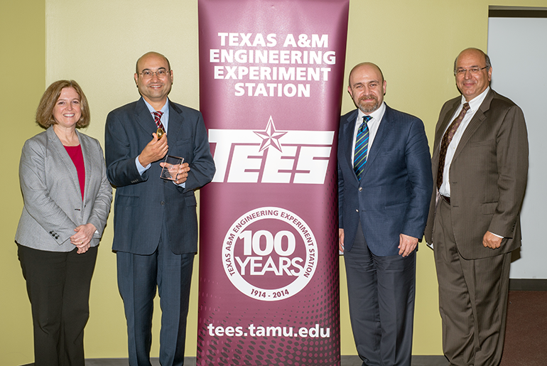 Dr. Banks and three individuals in front of banner with words of Texas A&amp;M Engineering Experiment Station TEES 100 Years.