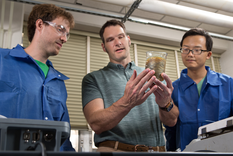 Dr. Jaime Grunlan discusses the behavior of a clay solution to two other Ph.D. students.