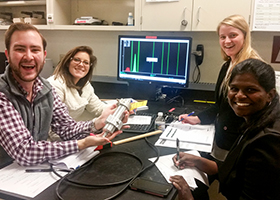 Image of a diverse group of individuals posing in front of a computer with simulated results