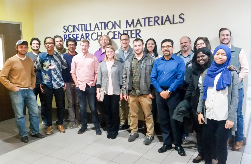 Group of nuclear engineering students posing in front of a "Scintillation Materials Research Center" sign.
