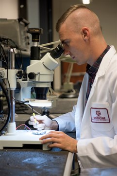 Researcher looking through a microscope.