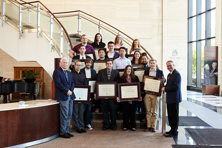 Distinguished Graduate Students standing on stairs holding their framed certificates