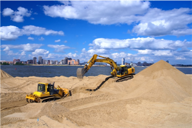 Heavy construction machines on coast moving sands.