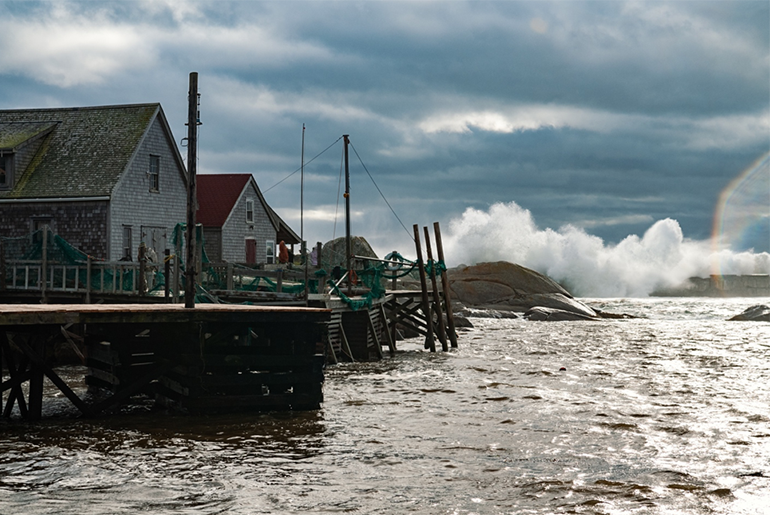 Houses on stilts in water with waves crushing in the background.