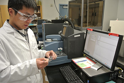 Male researcher in lab coat and eye protectors  examining in a lab.