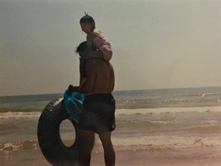 Father and daughter playing with a tire on the beach