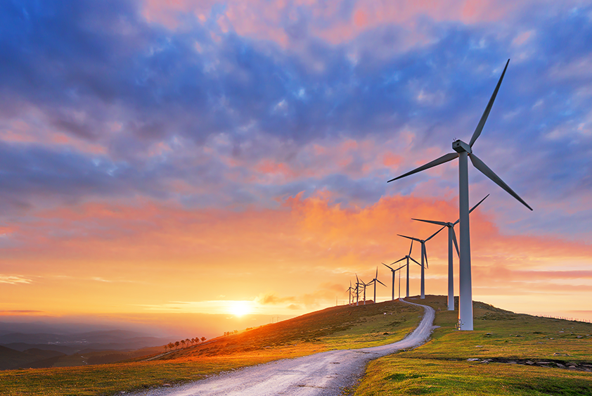 Wind turbines on a hill with a sunset background