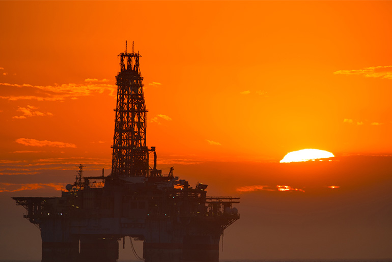 Oil rig and sunsetting in the background.