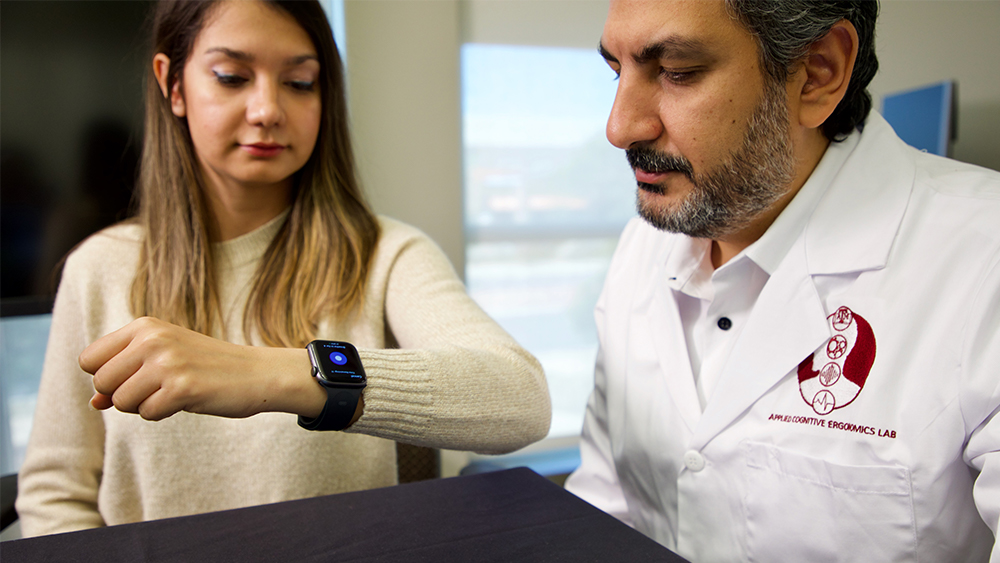 Scientist and young woman analyzing the smart watch's data