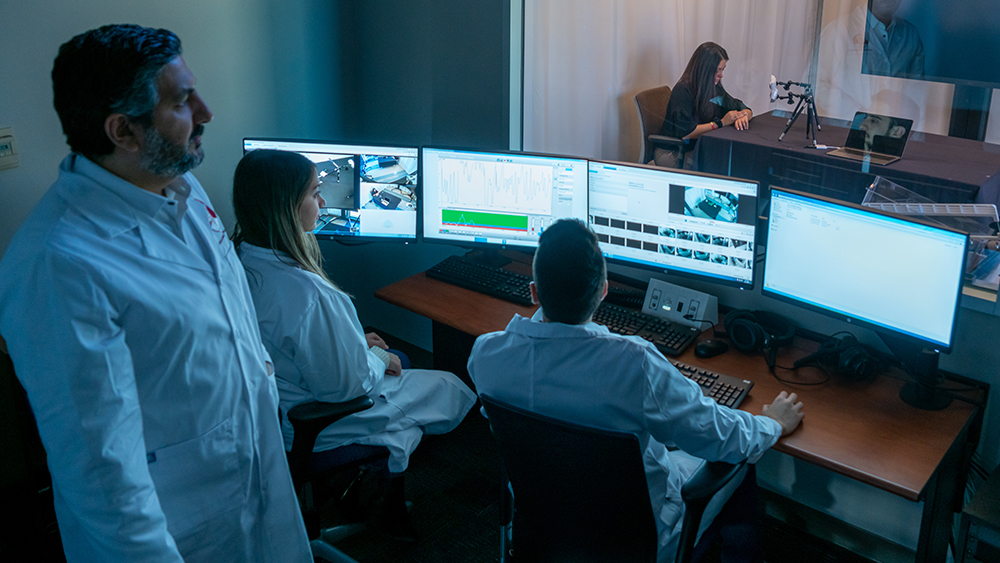 Scientists overlooking simulations and data in a dark-lit room