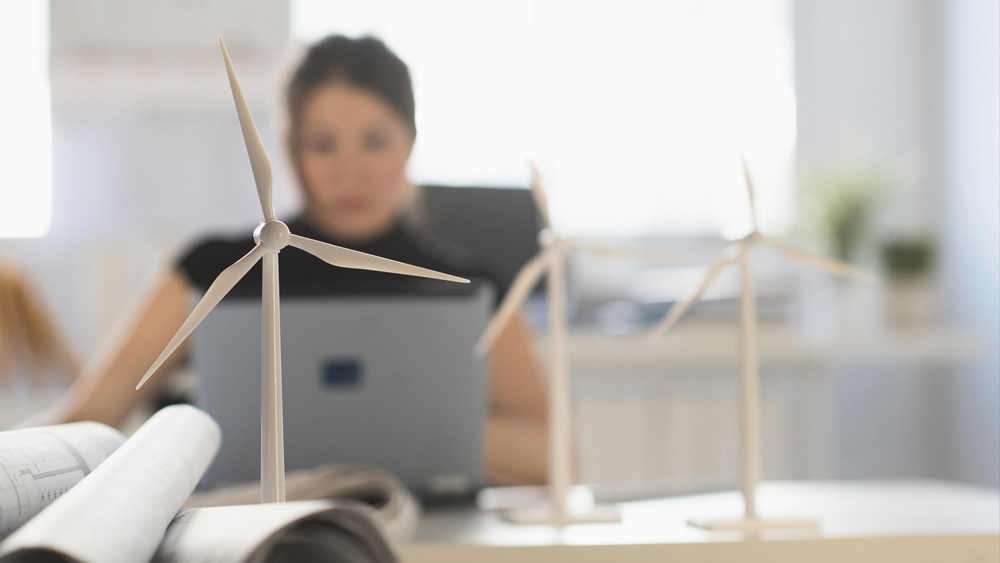 architect with windmill models using laptop