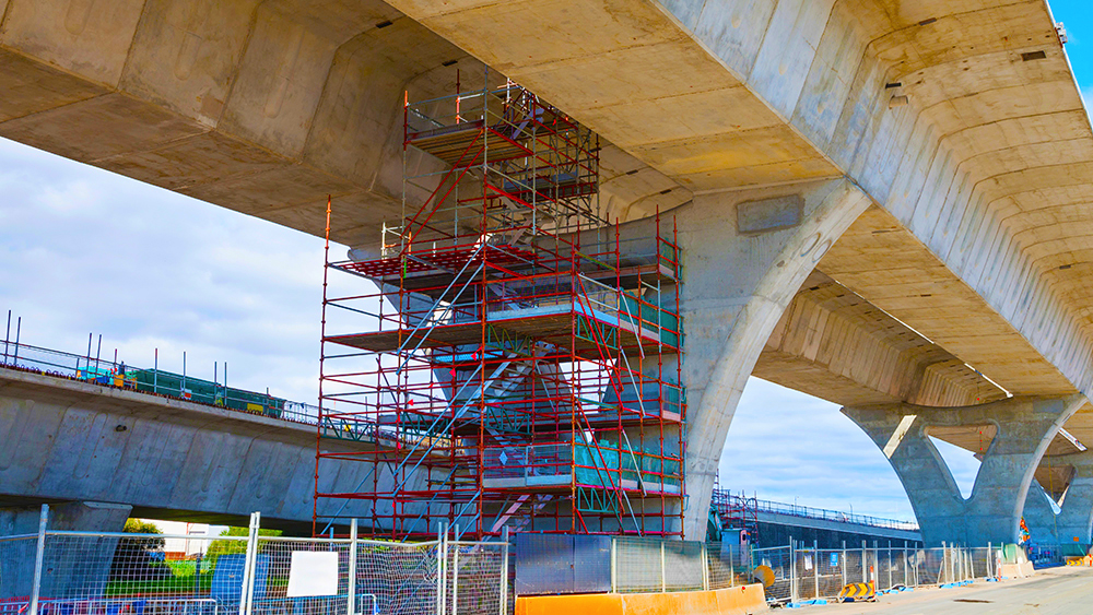 Bridge under construction with red scaffolding beneath it.