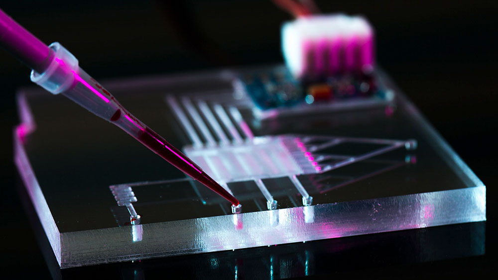 A pipette squirting liquid into a microfluidic device