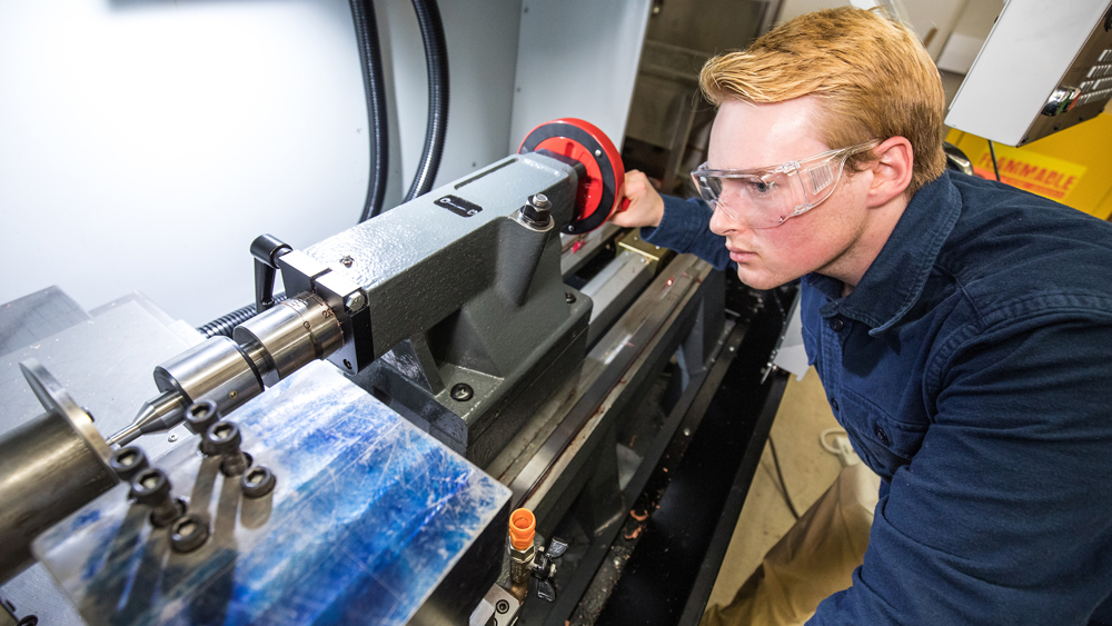 Texas A&amp;M graduate student Matthew Stahr leans over equipment as he observes the MetPeel process. 