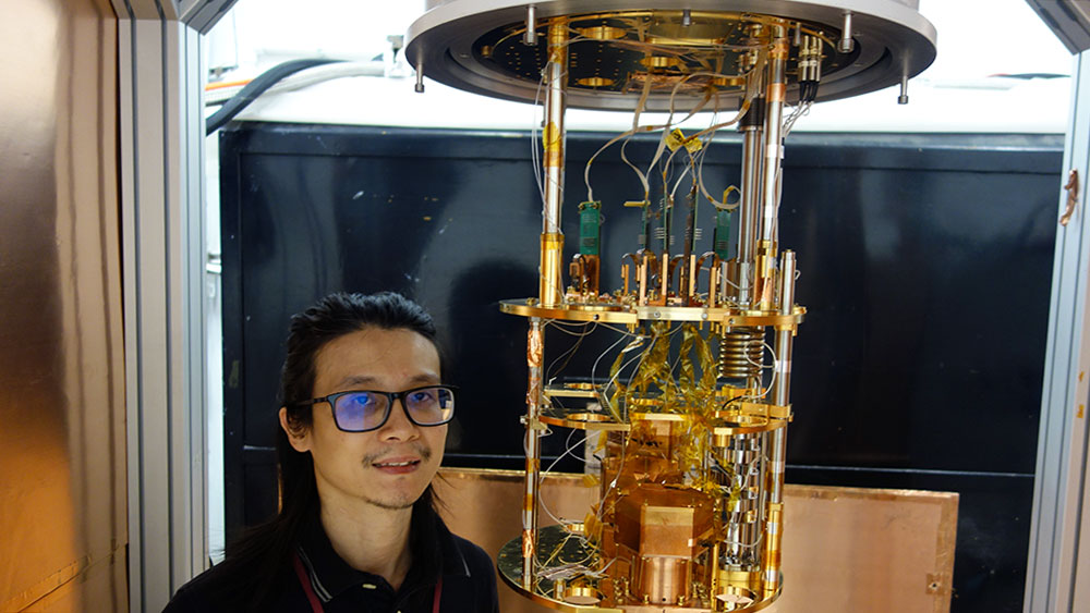 Texas A&M University graduate student Wei Eng Ang standing next to piece of equipment at the Mitchell Institute Neutrino Experiment at Reactor site at the Texas Engineering Experiment Station’s Nuclear Engineering and Science Center.