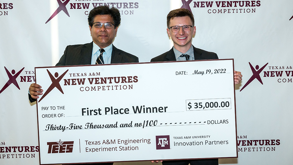 Dr. Saurabh Biswas and Bryton Praslicka holding a large first-place check for $35,000 from the Texas A&M New Ventures Competition. Texas A&M Engineering Experiment Station and Texas A&M University Innovation Partners logos are at the bottom of the check.