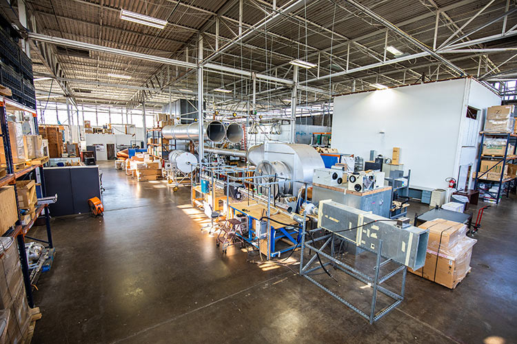 The inside of a large hangar with machines and tools for testing airflow systems.