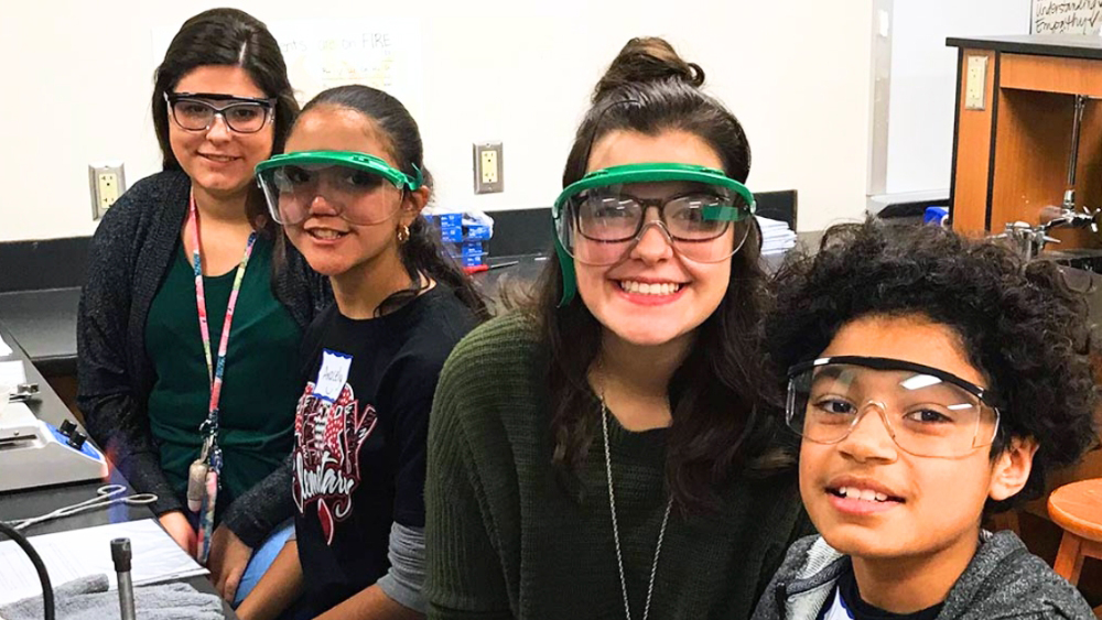 four smiling people wearing safety glasses